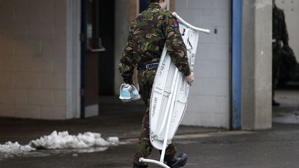 Un membre du&nbsp;Royal Horse Artillery d&eacute;m&eacute;nage sa planche &agrave; repasser. Cette unit&eacute; de l'arm&eacute;e britannique quitte ses anciens locaux pour une nouvelle r&eacute;sidence &agrave; Woolwich Garrison, Londres, le 6 f&eacute;vrier 2012. (STEFAN WERMUTH / REUTERS)