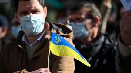 Un manifestant tient un drapeau ukrainien durant un rassemblement à Rennes contre l'invasion russe, le 26 février 2022. (DAMIEN MEYER / AFP)