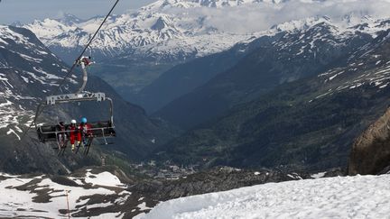 Les skieurs sont assis sur un téléski pour se rendre au sommet le jour de l'ouverture de la saison de ski d'été de Val d'Isère en Savoie, le 3 juin 2018. (ROMAIN LAFABREGUE / AFP)