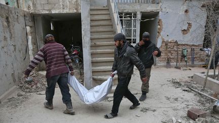 Des Syriens portent le corps d'une personne morte dans l'effondrement d'un immeuble, après une frappe aérienne à Haza, dans la Ghouta orientale (Syrie), le 26 février 2018.&nbsp; (ABDULMONAM EASSA / AFP)