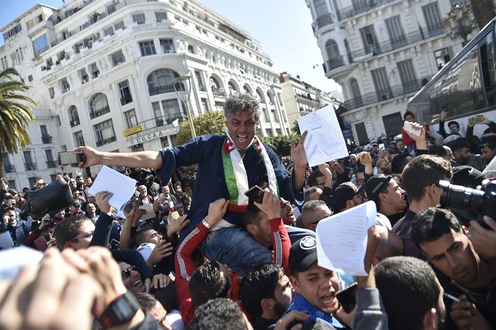 L'homme d'affaires Rachid Nekkaz, candidat déclaré à l'élection présidentielle algérienne, porté par la foule lors d'une manifestation de ses partisans à Alger, le 23 février 2019. (RYAD KRAMDI / AFP)