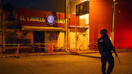 Un policier monte la garde devant le bar Caballo Blanco, où 25 personnes ont été tuées lors d'un incendie, le 28 août 2019, à Coatzacoalcos (Mexique). (VICTORIA RAZO / AFP)