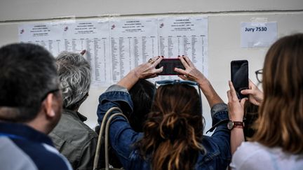 Des parents prennent en photo les résultats du baccalauréat devant le lycée Fresnel à Paris, le 5 juillet 2019. (STEPHANE DE SAKUTIN / AFP)