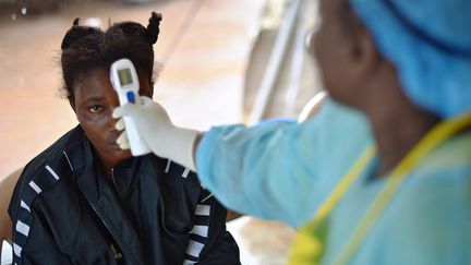 Une soignante vérifie la température d'une patiente après une suspicion d'infection au virus Ebola, le 16 août 2014, dans un hôpital de Kenema (Sierra Leone). (CARL DE SOUZA / AFP)