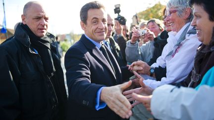 Nicolas Sarkozy salue des badauds avant une table ronde avec des agriculteurs, mardi 29 novembre &agrave; Gimont (Gers). (FREDERIC LANCELOT / SIPA)