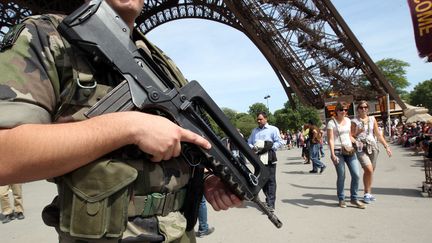 Un soldat patrouille&nbsp;au pied de la tour Eiffel, dans le cadre du plan Vigipirate, le 7 mai 2011 &agrave; Paris. (THOMAS SAMSON / AFP)