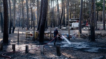 Un pompier arrose le sol encore chaud afin d'empêcher un nouveau départ d'incendie, à Cazaux (Gironde), le 24 juillet 2022. (VALENTINO BELLONI / HANS LUCAS / AFP)