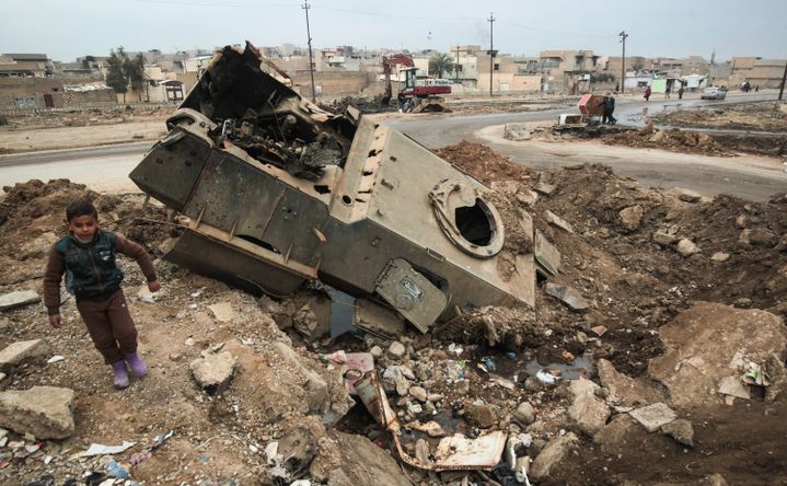 Dans un quartier est de Mossoul, le 21 janvier 2017, un enfant se tient près d'un véhicule détruit par les affrontements entre les forces irakiennes et Daesh (AHMAD AL-RUBAYE / AFP)