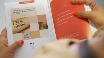 Une femme lit un document sur les droits à l'avortement, le 1er juillet 2022, dans un centre de santé à Paris. (GEOFFROY VAN DER HASSELT / AFP)