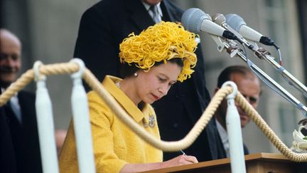 La reine Elizabeth à Berlin, le 27 mai 1965. La reine est venue en visite au RFA. La reine vinet juste après la visite de Kennedy et pour les autorités est-allemandes c'est un non-evenement. Lorsqu'elle part à la porte de Branckbourg, il y a beaucoup de curieux qui veulent voir la reine. Les magazines anglais ont titré que la reine a donné une grande leçon d'optimisme et de mode aux Allemands. Ce chapeau est un monument d'histoire et un monument de mode. Il a été réalisé par Simone Mirman qui est une modiste française.&nbsp; (KURT ROHWEDDER / DPA)