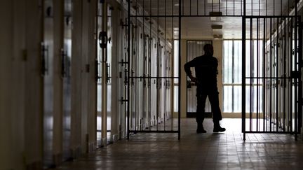 Un surveillant patrouille dans un couloir de la prison de Bois-d'Arcy (Yvelines), le 8 juillet 2014. (KENZO TRIBOUILLARD / AFP)