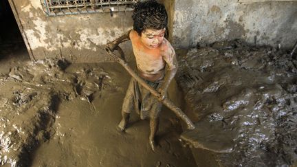 Un jeune gar&ccedil;on nettoie la boue de sa maison apr&egrave;s des inondations &agrave; Iligan (Philippines), le 21 d&eacute;cembre 2011. (ERIK DE CASTRO / REUTERS)