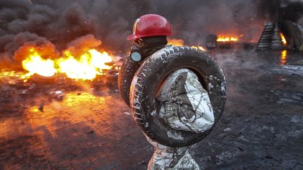 Un manifestant pro-europ&eacute;en transporte des pneus pour les br&ucirc;ler &agrave; Kiev (Ukraine) sur le lieu des affrontements avec les forces de l'ordre, le 23 janvier 2014. (REUTERS)