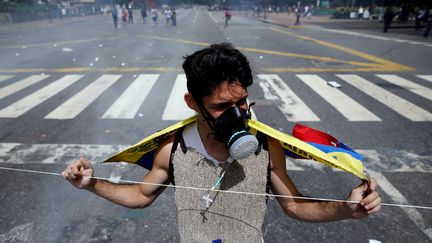 Un manifestant porte un masque anti-gaz durant une manifestation à Caracas, le 10 juillet 2017. (CARLOS GARCIA RAWLINS / REUTERS)