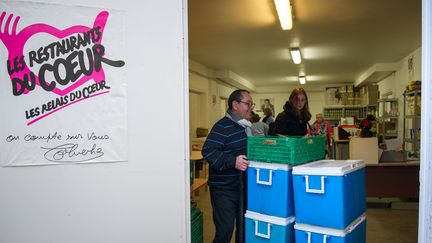 Des bénévoles des Restos du Coeur transportent des denrées dans un entrepôt à Tours (Indre-et-Loire). (GUILLAUME SOUVANT / AFP)