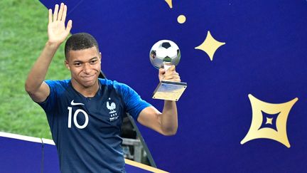 L'attaquant des Bleus, Kylian Mbappé, soulève son trophée du meilleur jeune de la Coupe du monde, dimanche 15 juillet 2018 à Moscou (Russie). (ALEXANDER NEMENOV / AFP)