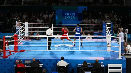 Sofiane Oumiha et Erislandy Alvarez Borges sur le court Philippe-Chatrier, aménagé en ring de boxe, le 7 août 2024 (MOHD RASFAN / AFP)