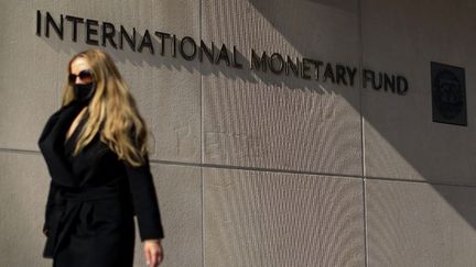 Photo d'archive prise le 5 avril 2021&nbsp;d'une femme passe devant le siège du Fonds monétaire international à Washington (Etats-Unis). (MANDEL NGAN / AFP)