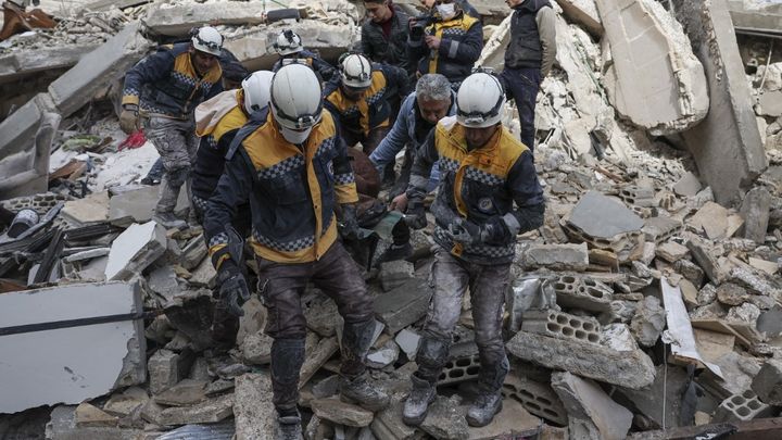 Des Casques blancs transportent un blessé extrait des décombres dans le village d'Azmarin, au nord-ouest de la Syrie, le 7 février 2023. (OMAR HAJ KADOUR / AFP)