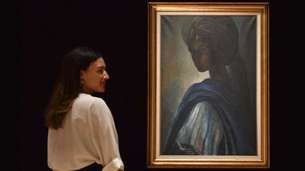 Une employée de la maison d'enchères Bonhams pose près du portrait de la princesse "Tutu" de Ben Enwonwu, à Londres (7 février 2018)
 (Ben Stansall / AFP)