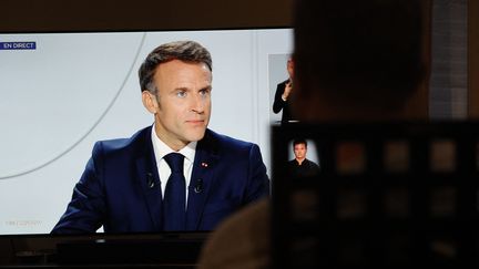 Un homme regarde l'entretien d'Emmanuel Macron aux "20 Heures" de TF1 et France 2, le 24 septembre 2023. (GEOFFROY VAN DER HASSELT / AFP)