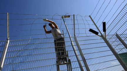 Un homme installe des fils barbel&eacute;s au&nbsp;centre de r&eacute;tention de Vincennes (Paris), le 12 juin 2006. (FRED DUFOUR / AFP)