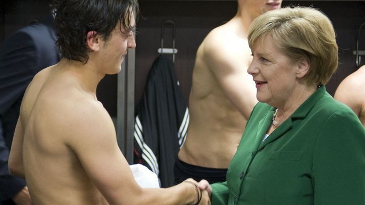 Angela Merkel salue le milieu de terrain Mesut &Ouml;zil dans les vestiaires apr&egrave;s un match Allemagne-Turquie (3-0), le 8 octobre 2010. (GUIDO BERGMANN / REUTERS)