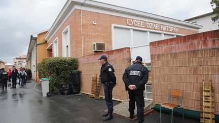 Des policiers montent la garde sur les lieux de la fusillade, devant le coll&egrave;ge-lyc&eacute;e juif Ozar-Hatorah, dans le quartier de la Roseraie, &agrave; Toulouse, le 19 mars 2012. (ERIC CABANIS / AFP)