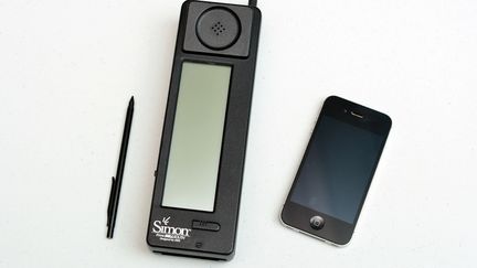 L'IBM Simon, premier téléphone tactile, a été commercialisé à partir du 16 août 1994. Il est disposé à côté d'un iPhone, en 2014 au Science Museum de Londres. Illustration. (CARL COURT / AFP)