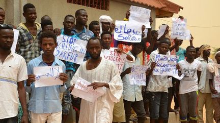 Des migrants portent des affichettes dénonçant des violences contre des réfugiés à Agadez, au Niger (21 juin 2018). (BOUREIMA HAMA/AFP)