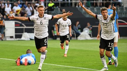 Joshua Kimmich (à gauche) et Thomas Müller (à droite), célèbrent l'ouverture du score de l'Allemagne en Ligue des nations contre l'Italie, le 14 juin 2022. (FEDERICO GAMBARINI / AFP)