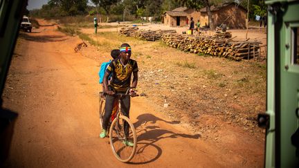 Deux garçons font du vélo sur une route supposée sûre, évitant les axes où sont disséminés des engins explosifs, à Paoua, dans le nord-ouest de la République centrafricaine, le 5 décembre 2021. (BARBARA DEBOUT / AFP)