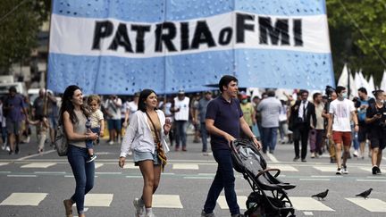 Des manifestants tiennent un drapeau sur lequel on peut lire "Patrie ou FMI" lors d'une manifestation&nbsp;à Buenos Aires (Argentine), le 17 mars 2022. (JUAN MABROMATA / AFP)