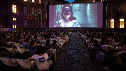 Des spectateurs regardent "La Reine Margot" dans la Cour Carrée du Louvre (Paris) dans le cadre du festival de cinéma en plein air Cinema Paradiso, le 19 juillet 2019. (MARTIN BUREAU / AFP)