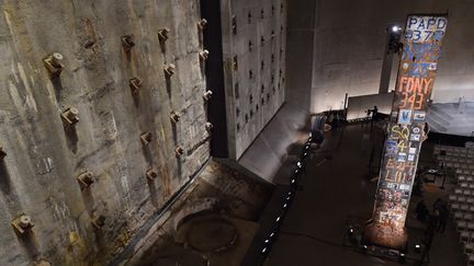 La "dernière colonne" (à droite) en acier massif, ancien support intérieur de la tour sud du Word Trade Center, est la dernière poutre à avoir été retirée de Ground Zero. À gauche, un énorme segment d'un ancien mur de fondation construit pour protéger le site des inondations de l'Hudson River, au Musée du 11-Septembre, à New York (14 mai 2014)
 (Stan Honda / AFP)