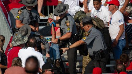 Une personne est évacuée des tribunes par la police de l'Etat de Pennsylvanie après les tirs qui ont visé Donald Trump, le 13 juillet 2024 dans la ville de Butler. (REBECCA DROKE / AFP)