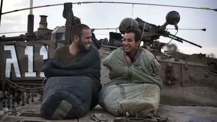 Deux soldats isra&eacute;liens se r&eacute;veillent sur le toit de leur tank pr&egrave;s de la fronti&egrave;re entre Isra&euml;l et la bande de Gaza, jeudi 22 novembre. (MENAHEM KAHANA / AFP)