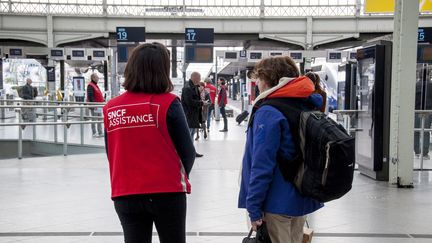 Une employée de la SNCF aide une voyageuse à la&nbsp;gare de Lyon, à Paris, le 13 avril 2018, jour de grève au sein du groupe. (DAVID SEYER / AFP)