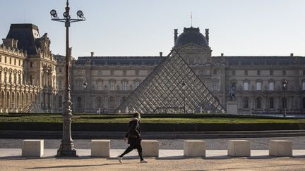 Un passant devant la pyramide du Louvres et une esplanade déserte en novembre 2020. (EMMA BUONCRISTIANI / HANS LUCAS)