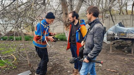 Viktor dans son jardin qui a résisté aux bombardements russes, à Borodianka. "Viktor est fier de montrer à Roman Sigov, notre fixeur, et Fabien Gosset, le technicien de reportage, ses petits pots de lys dans son jardin qui ont résisté aux bombardements russes, comme un symbole." (FARIDA NOUAR / FRANCEINFO / RADIO FRANCE)