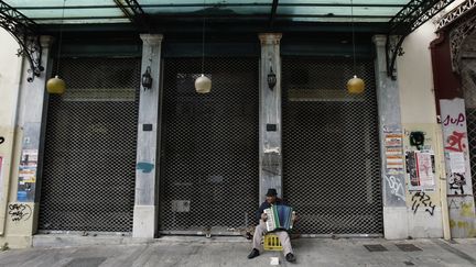 Un musicien joue de l'accord&eacute;on devant un magasin ferm&eacute; &agrave; Ath&egrave;nes (Gr&egrave;ce), lundi 30 janvier 2012. (JOHN KOLESIDIS &nbsp;/ REUTERS)