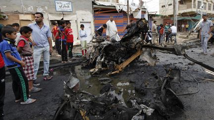 Des habitants constatent les d&eacute;g&acirc;ts caus&eacute;s par une attaque &agrave; la voiture pi&eacute;g&eacute;e, le 20 mai 2013, &agrave; Bagdad (Irak). (MOHAMMED AMEEN / REUTERS)