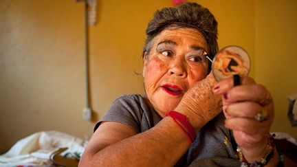 se prépare avant de sortir travailler dans les rues de La Merced. Elle porte une perruque et un soutien-gorge rembourré. Elle est venue habiter dans la casa Xochiquetzal dès son ouverture. C’est une femme très gaie : elle a la conversation et la chanson faciles. Cela fait 22 ans qu’elle est atteinte de schizophrénie, mais bien qu’elle entende des voix, elle travaille pour ne pas perdre contact avec la réalité. Pour gagner un peu d’argent, elle collecte également des bouteilles en plastique pour le recyclage et aide son compagnon plus jeune à vendre des vêtements. (Bénédicte Desrus )