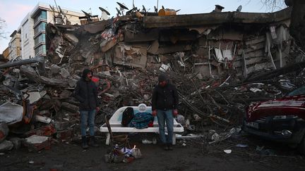 Des hommes devant les décombres d'un immeuble à Kahramanmaras,&nbsp;en Turquie, le 7 février 2023.&nbsp; (OZAN KOSE / AFP)