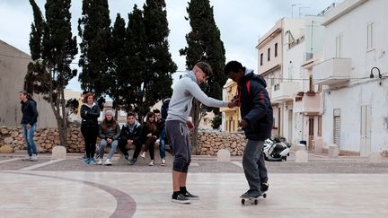 Un Italien apprend &agrave; un migrant somalien &agrave; faire du skate &agrave; Lampedusa (Italie), le 20 f&eacute;vrier 2015. (ALBERTO PIZZOLI / AFP)