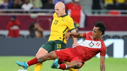 L'Australien Aaron Mooy contre le Péruvien Santiago Ormeno lors du match de barrage pour la qualification en Coupe du monde de football, le 13 juin 2022, à Doha (Qatar). (KARIM JAAFAR / AFP)