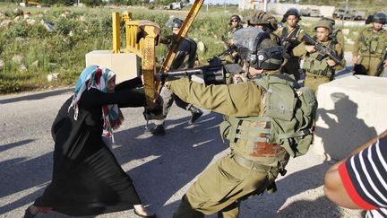 Une Palestinienne se heurte &agrave; un soldat isra&eacute;lien alors qu'elle tente de forcer un barrage &agrave; l'entr&eacute;e du village de Nabi Saleh pr&egrave;s de Ramallah (Palestine), le 14 avril 2014. (MOHAMAD TOROKMAN / REUTERS)