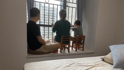 Yan, son mari et son fils devant la fenêtre de leur appartement dans la ville de Shenzhen, le 28 mars 2020. (DR)