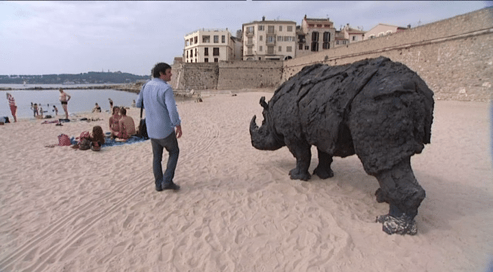 L'artiste italien Davide Rivalta sur la plage au côté de son impressionnant rhinocéros de bronze
 (Culturebox / Capture d&#039;écran)