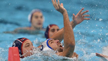 Le Serbe Nemanja Ubovic à la lutte avec l'Américain Hannes Daube, lors de la demi-finale du tournoi olympique de water-polo, à l'Arena de Paris La Défense, le 9 août 2024. (ANDREAS SOLARO / AFP)